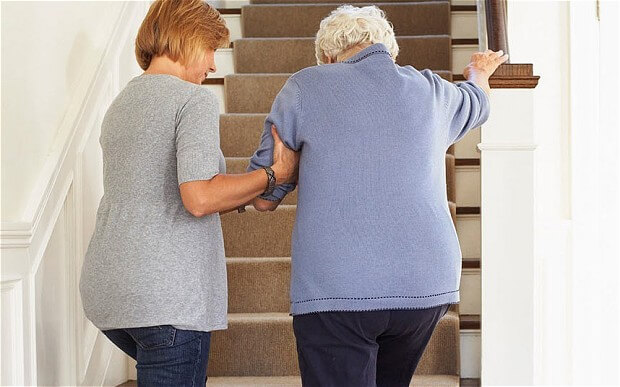 Older woman helping elderly lady go up flight of stairs