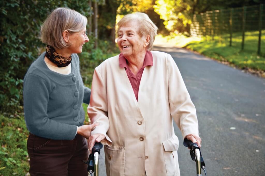 Senior woman accompanying an elderly lady with a walker in a park